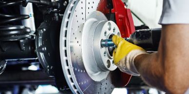 Mechanic installing a brake disc on a car wheel hub.